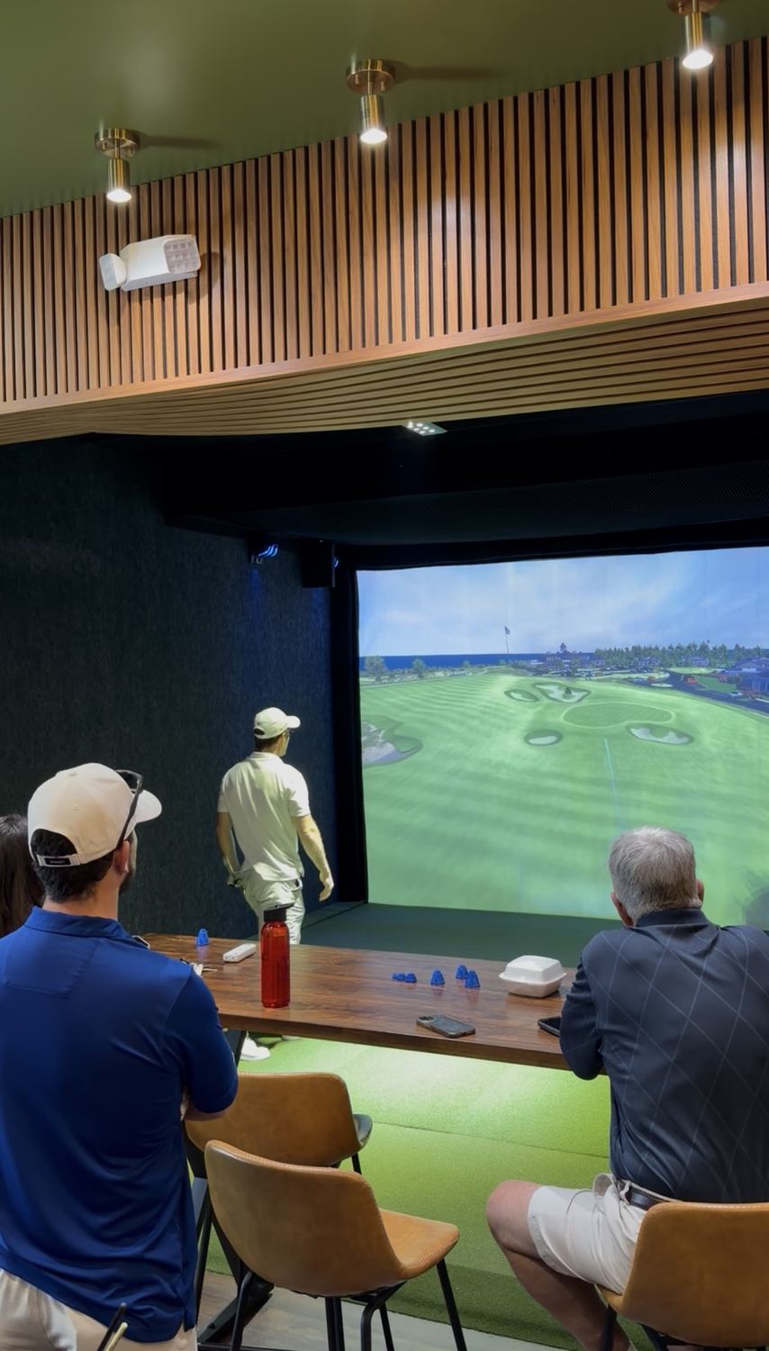 Two golfers watch a shot on a Full Swing simulator at Back Nine